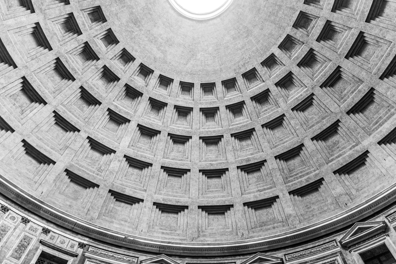 The coffered concrete dome of the Pantheon in Rome, seen from below, light falling through the oculus.